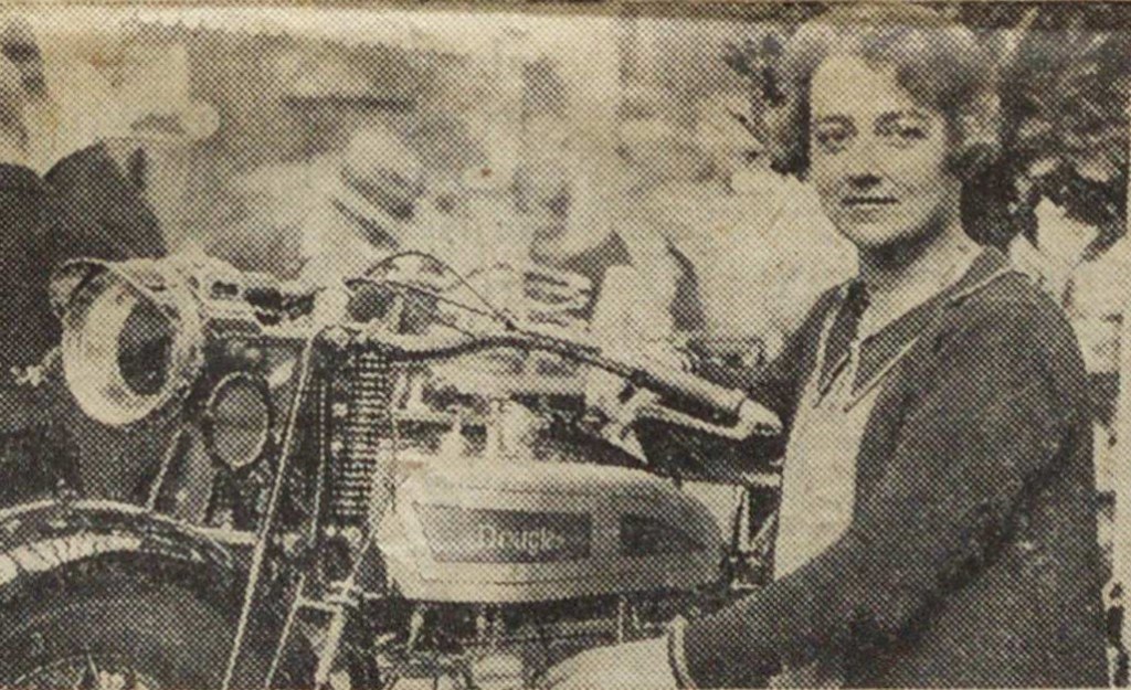 Young woman in 1920s clothing with a motorcycle.