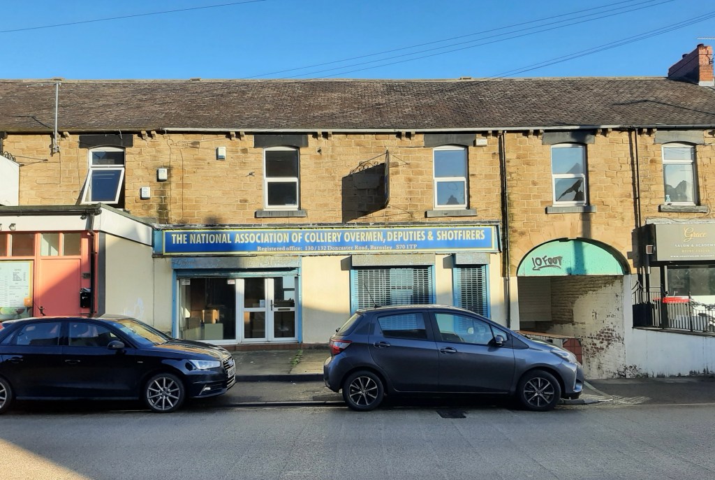 Shop front within a terrace of old brick buildings. The name of the union is on a board above the doors and windows.
